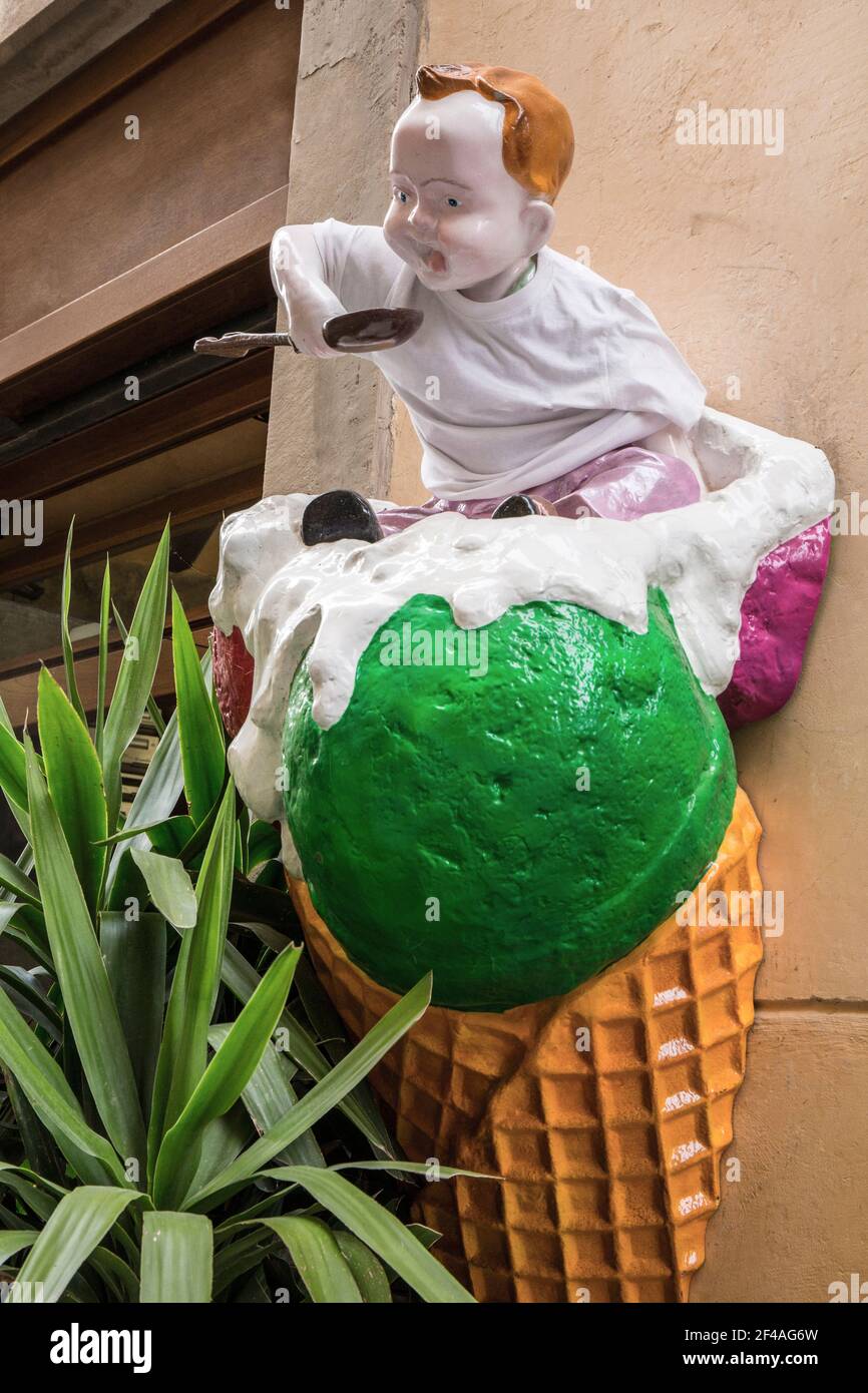 Cortona, Italien. Humorvolle Eisdiele Dekoration eines Jungen sitzt auf einem großen Eis-Kegel. (Nur für redaktionelle Zwecke) Stockfoto