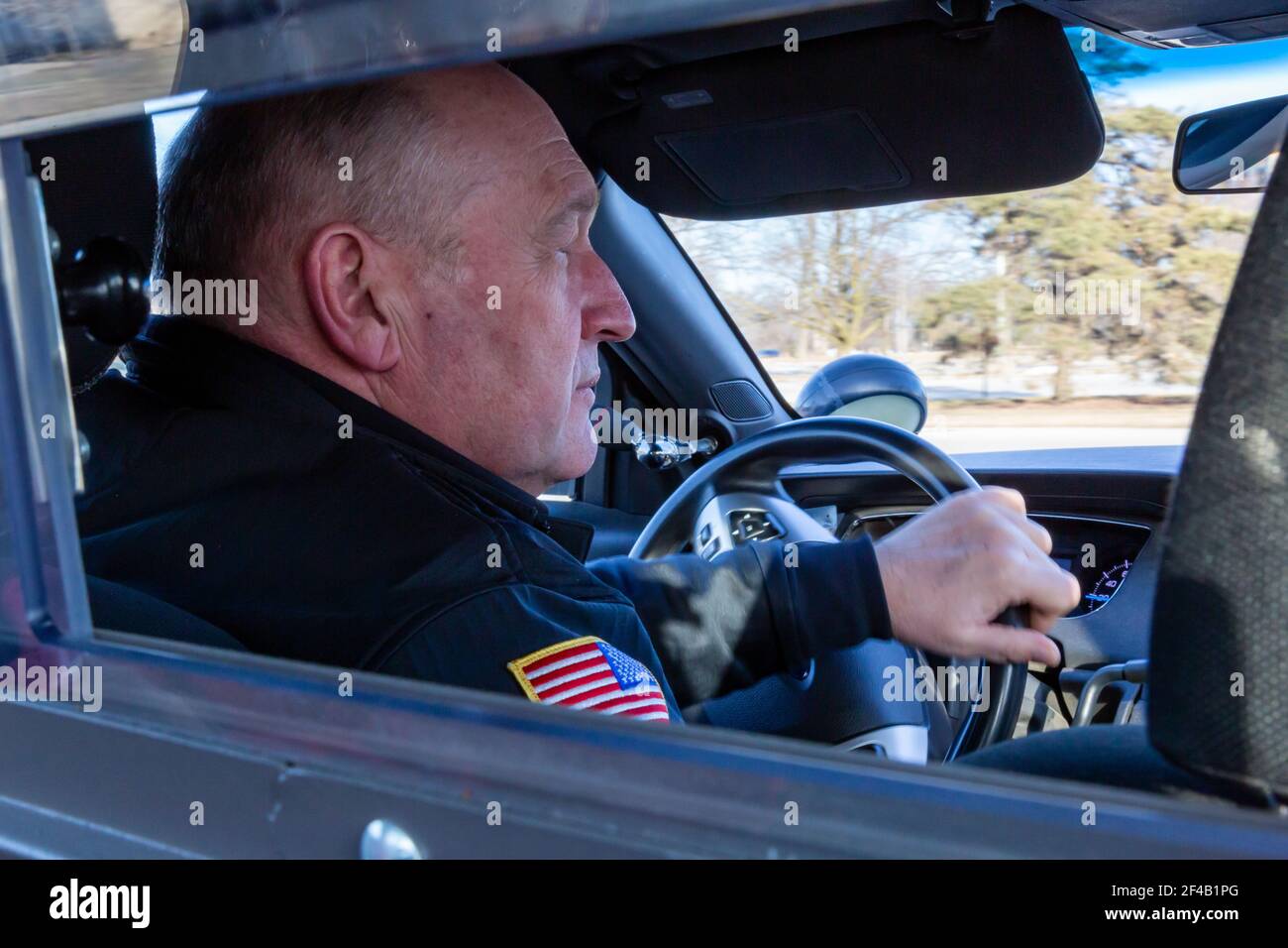Blick durch den Käfig auf einen uniformierten Polizisten, der einen Kaderwagen fährt. Stockfoto