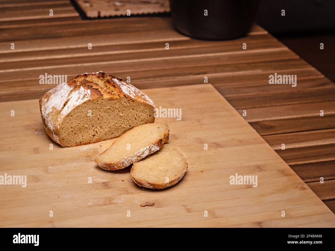 Geschnittenes Sauerteigbrot auf Schneidebrett. Rustikales hausgemachtes Brot. Zutaten: kamut 80%, Sauerteig Starter 10%, Backmalz, Allzweckmehl. Selektiv Stockfoto