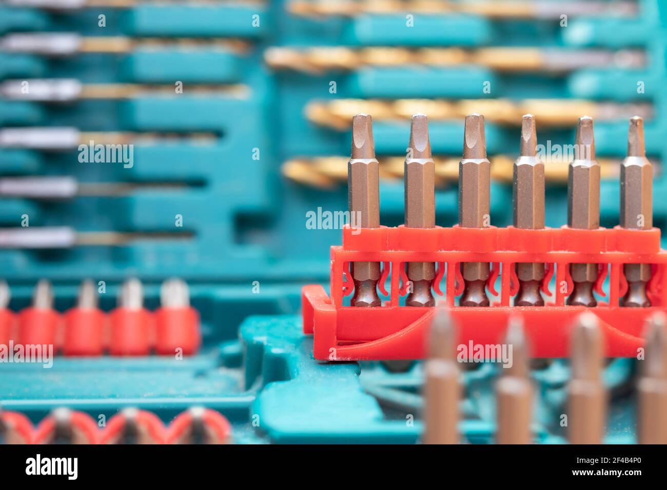 Bohrer-Kit, Nahaufnahme. Hintergrundstruktur der Hardware. Blaues Set mit einer Variante roter Bohrersätze und Schraubendreher. Defokussierte und abstrakte Sorten von Stockfoto