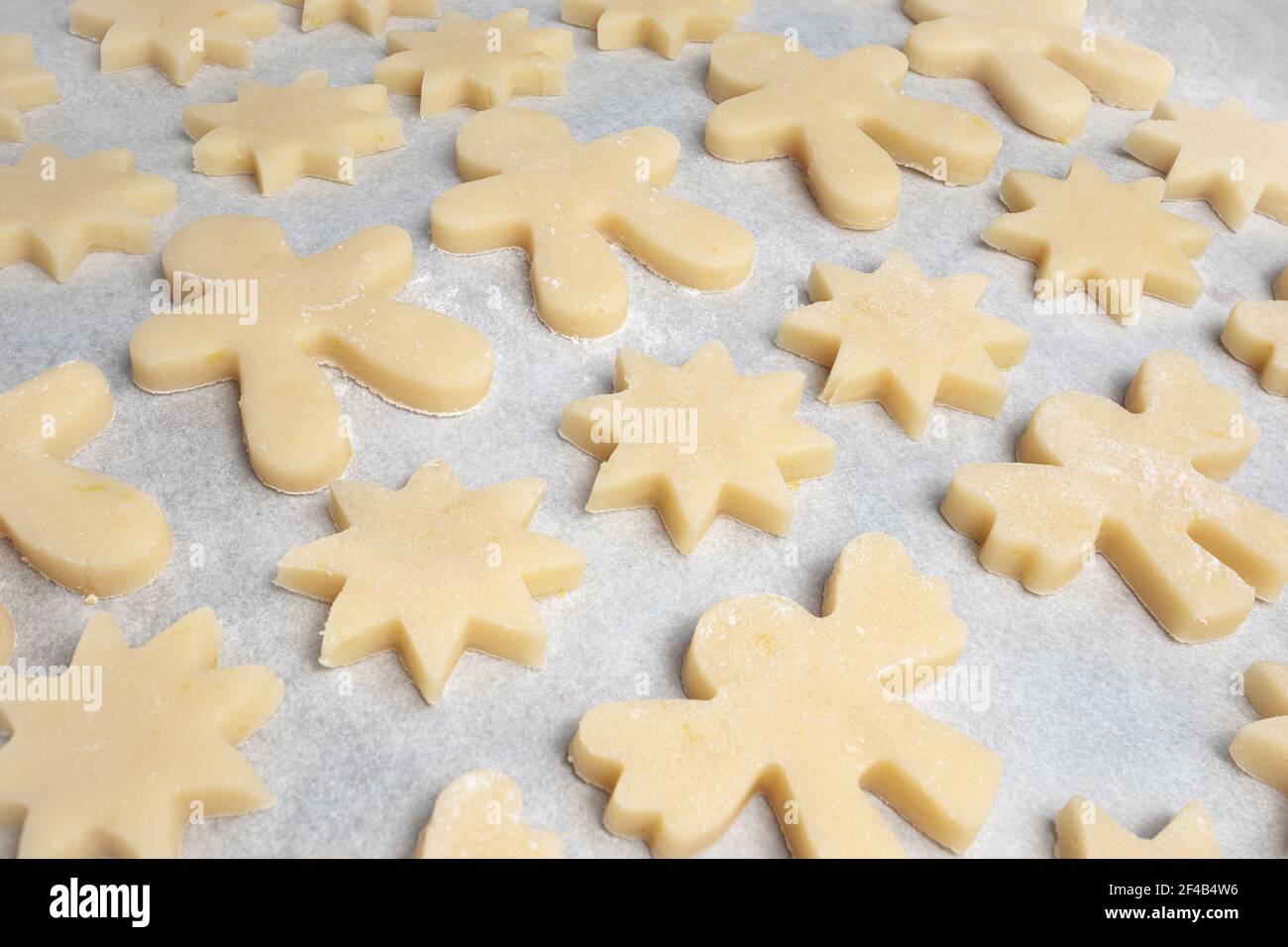 Viele Kekse auf Backblech. Diagonale Reihen von kurzen Brot Cookies Teig in verschiedenen Formen wie: Stern, Lebkuchen Mann und Engel. Herkömmlicher Chr Stockfoto
