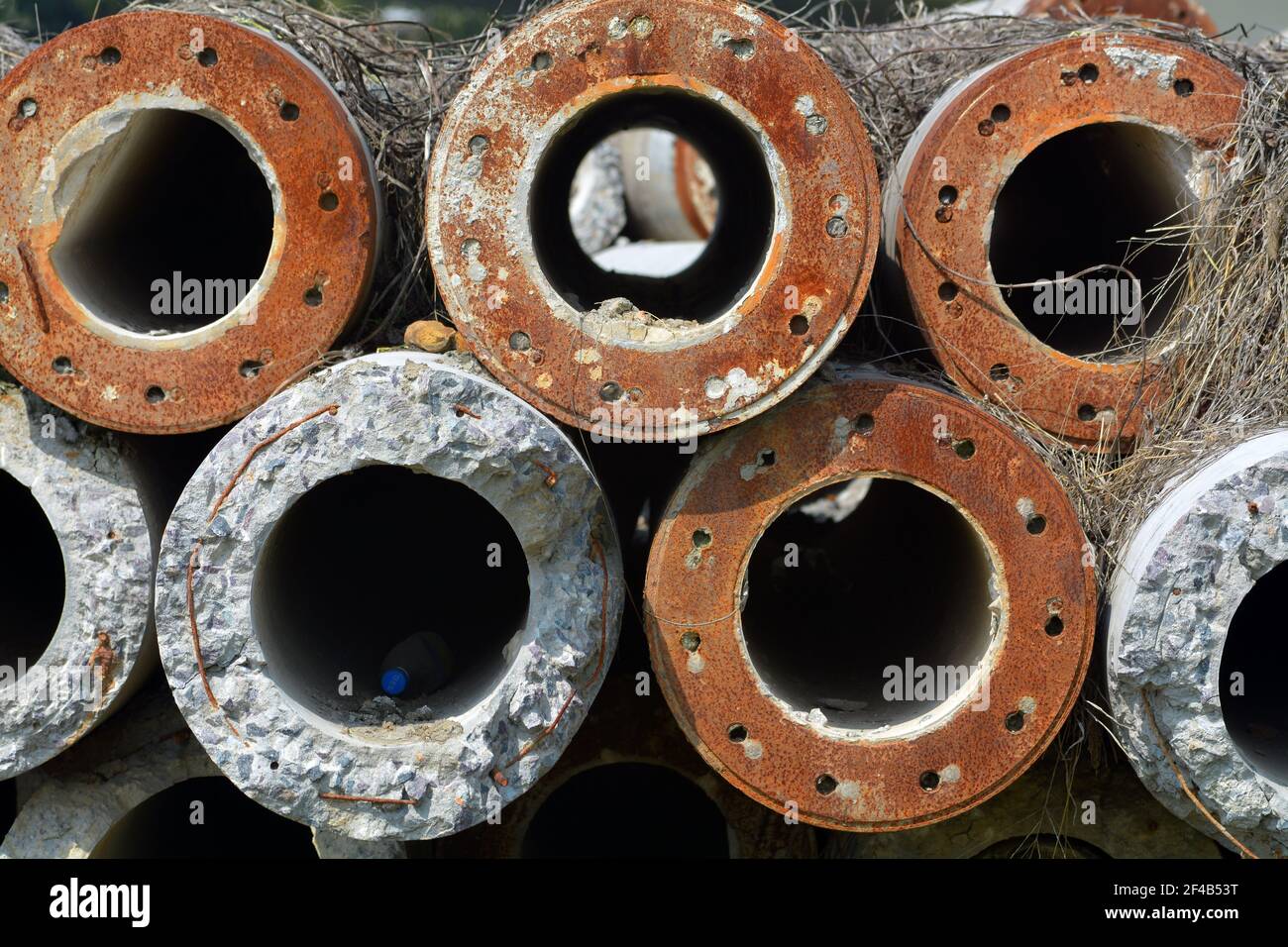 Alte Rohre gestapelt und ungenutzt in einem Feld irgendwo in China. Mischung aus Beton und verrosteten Altmetall. Stockfoto