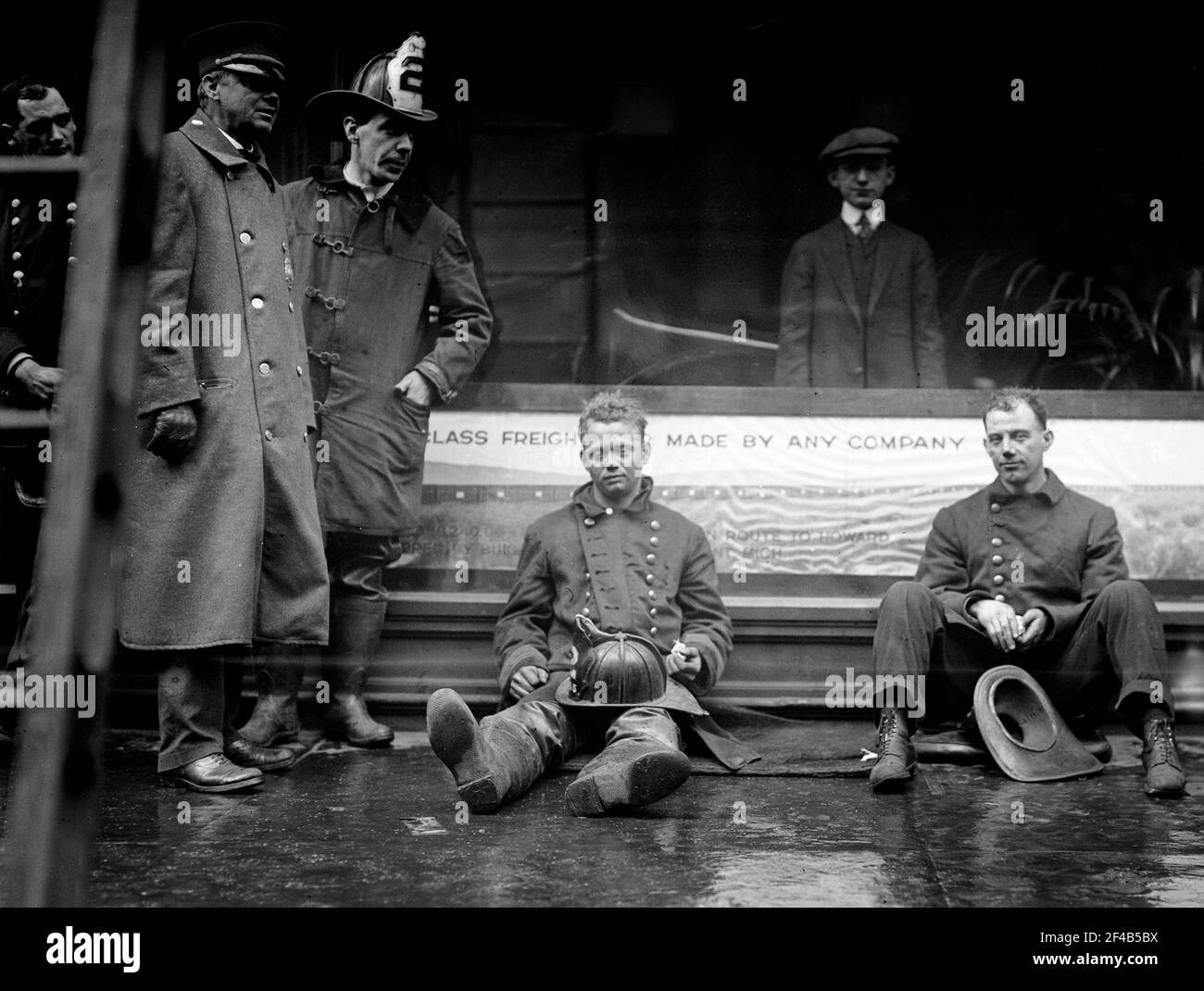 Feuerwehrleute saßen auf dem Bürgersteig, nachdem sie einen Brand in einem U-Bahn-Tunnel in New York City bekämpft hatten, der in der Nähe der West 55th Street und des Broadway am 6. Januar 1915 stattfand Stockfoto