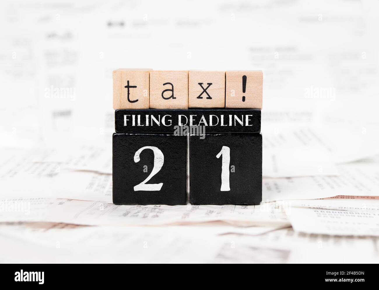 Steuerabgabefrist 2021 Konzept. Schwarze und hellbraune Holzblöcke mit steuerbezogenen Wörtern auf unverschämten Rechnungen, Rechnungen und Quittungen. Selektiv Stockfoto
