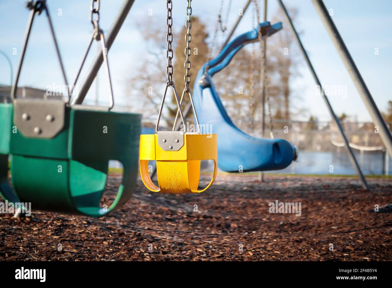Spielplatz Schaukel Set für Kleinkinder mit natürlichen Holz Mulch Boden für sparen. Selektiver Fokus auf gelben Vollschalensitz. Stockfoto