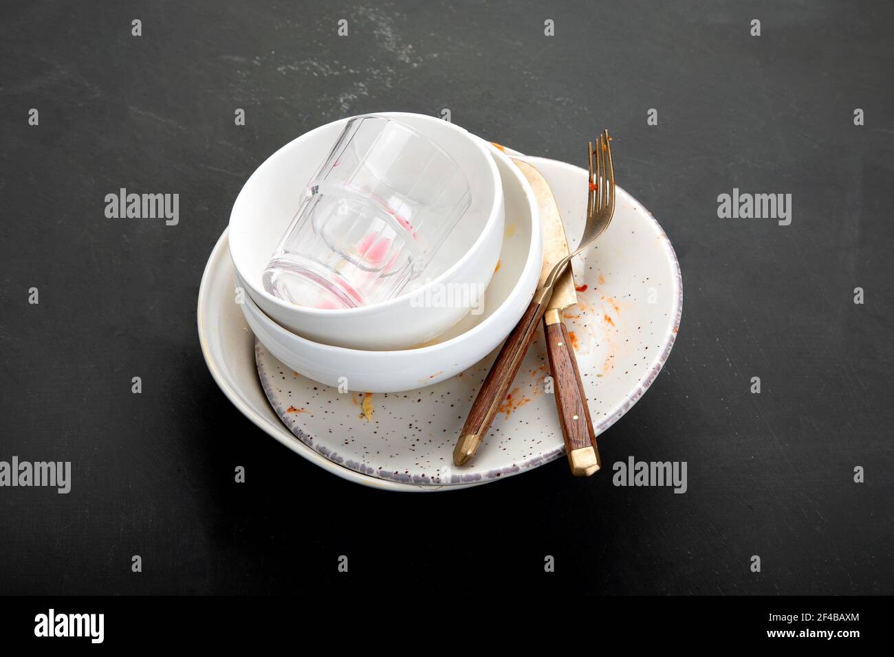 Stapel leerer und schmutziger Teller mit Essensresten auf dunklem Hintergrund. Stockfoto