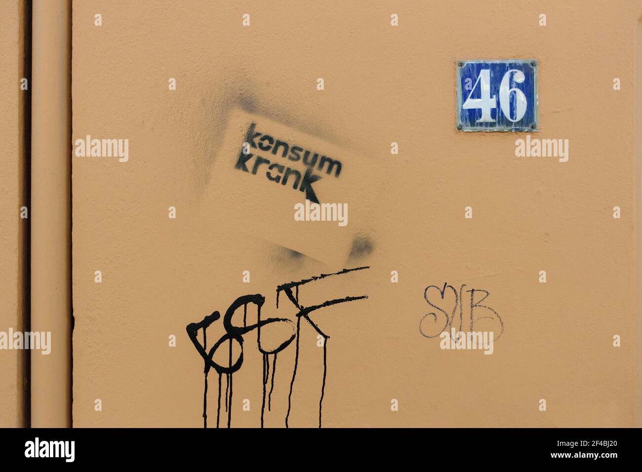 Schablonengraffiti - Konsum krank (konsum krank) - auf einer beige gemalten Hauswand mit der Hausnummer 46, Hamburg, Deutschland. Stockfoto