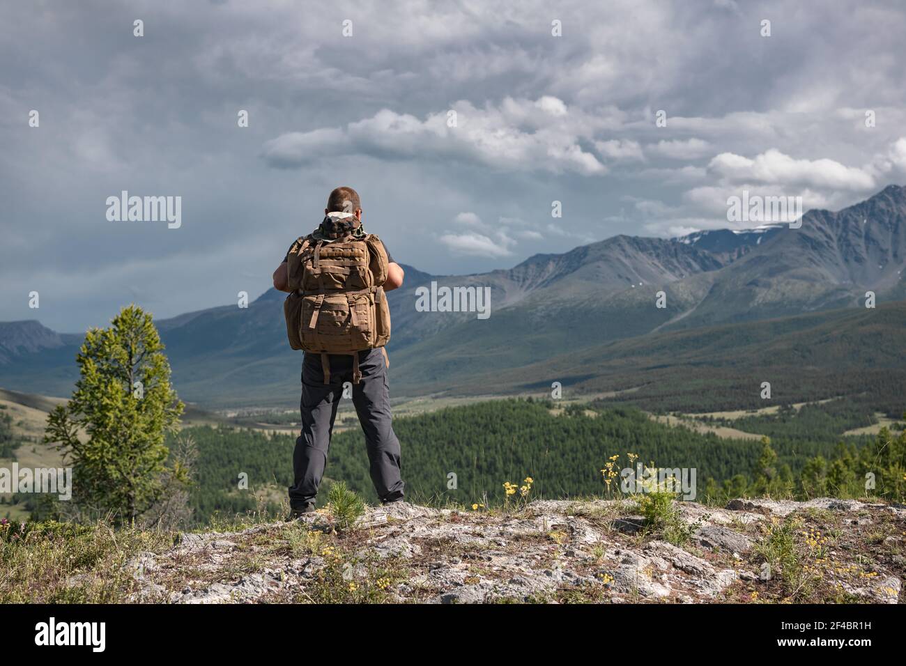 Wanderer mit Rucksack steht auf dem Hintergrund der Berge Stockfoto