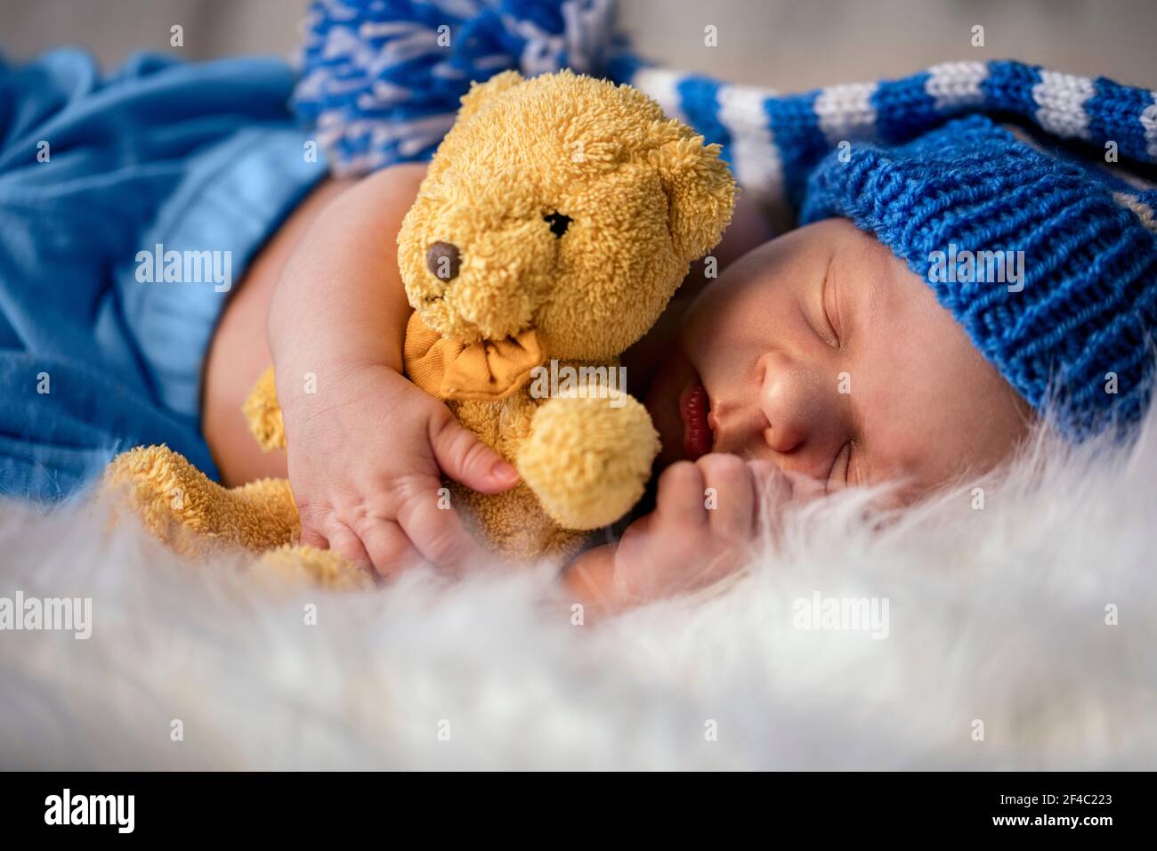 Schläfriges Neugeborenes mit weichem Teddybär auf weicher Decke Stockfoto