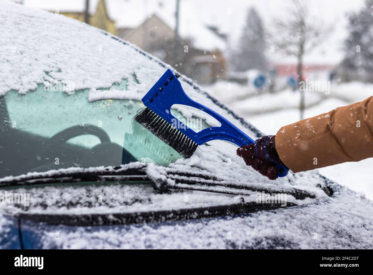 Reinigung der Windschutzscheibe von Schnee durch Eiskratzer mit Bürste im  Winter. Schnee vom Auto auf der Straße zu remagen Stockfotografie - Alamy