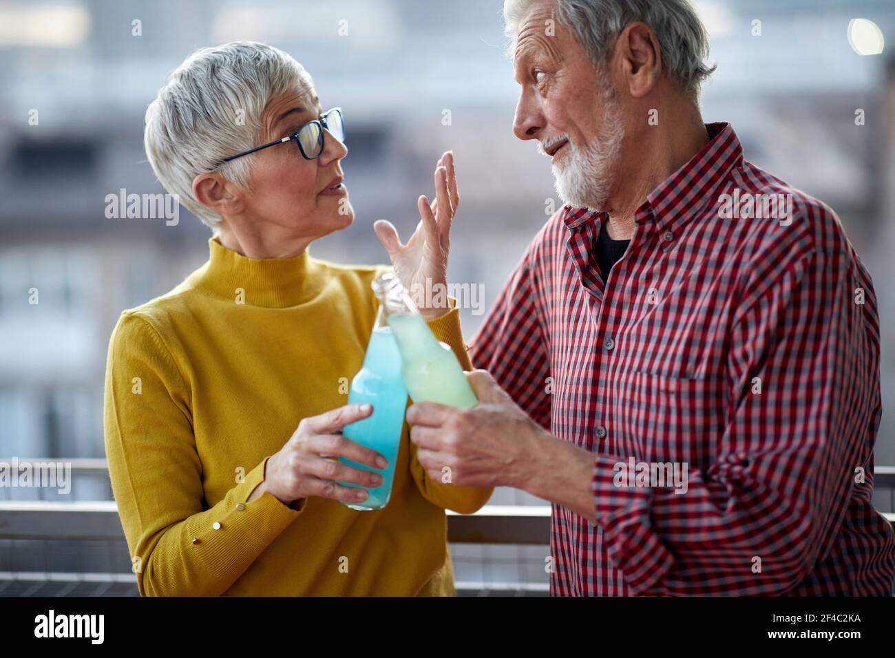Ein älteres Paar plaudert und genießt einen Drink in einer entspannten Atmosphäre auf der Terrasse bei schönem Sonnenuntergang über der Stadt. Beziehung, Liebe, zusammen Stockfoto