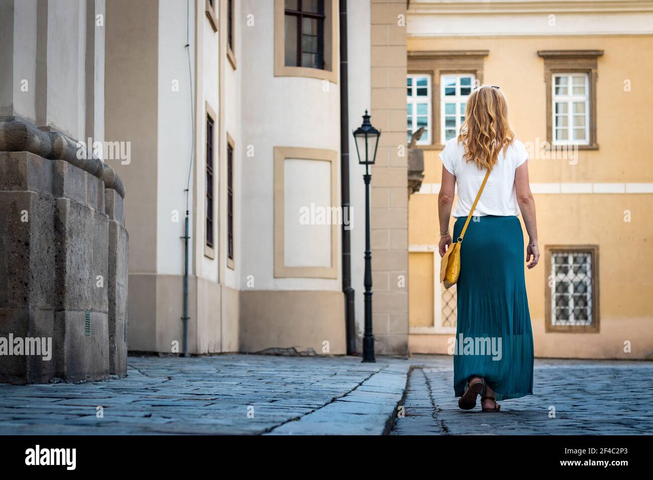 Frau in grünen Faltenrock gekleidet ist zu Fuß in der Altstadt. Casual Frau genießen Sommerurlaub in der europäischen Stadt Stockfoto