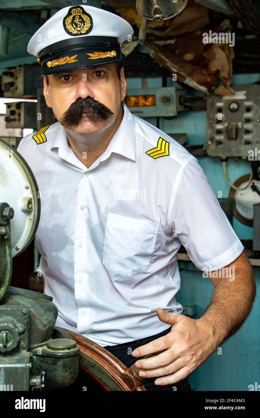Ein Matrose Offizier - alte Salz in der Uniform ist das Schiff mit einem Ruder. Kapitän im Ruderhaus des Schiffes und der Blick in die Kamera. Stockfoto