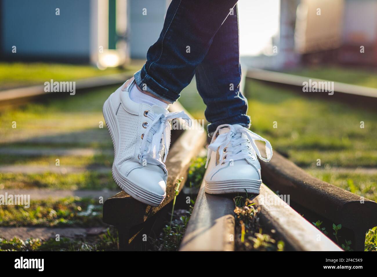 Frau in weißen Sneakers auf Schienen stehen. Sportschuh aus Leder. Stockfoto