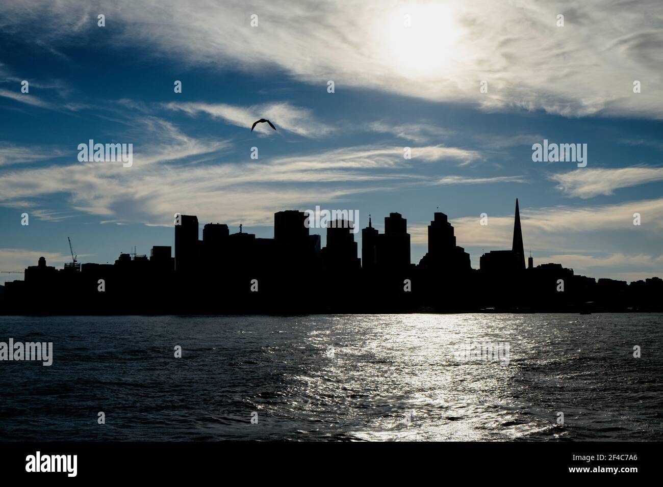 Die Skyline von San Francisco wird durch den Sonnenuntergang über der Bucht von San Francisco geschildet. Stockfoto