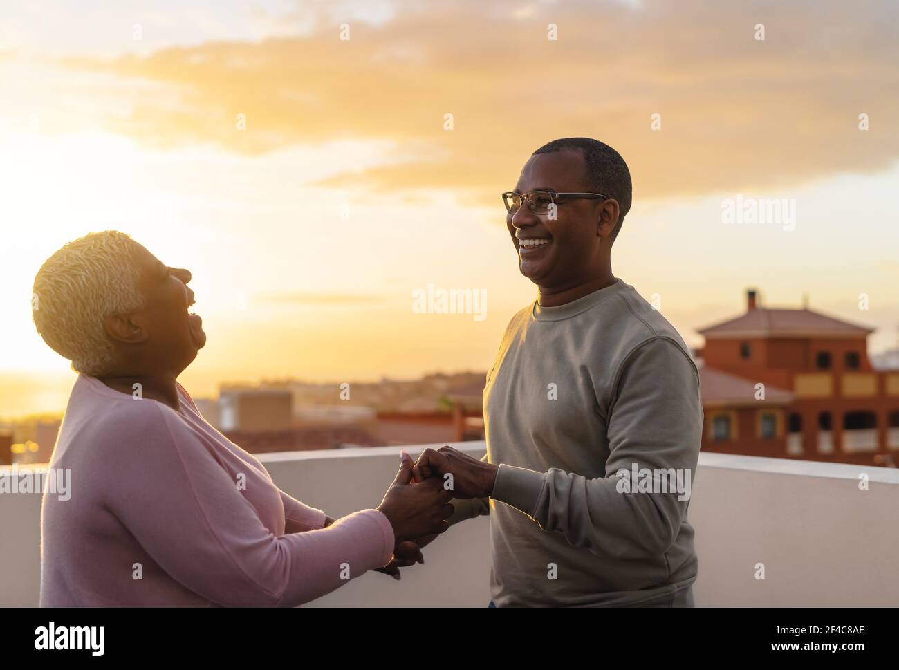 Glückliches lateinisches Seniorenpaar, das romantische Momente auf dem Dach tanzt Während der Sonnenuntergangszeit Stockfoto