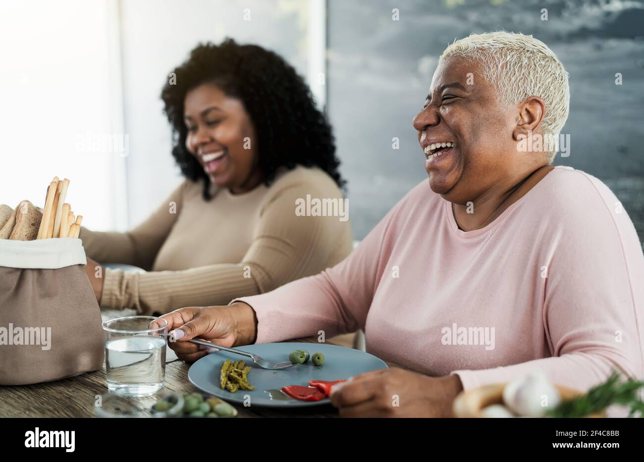 Glückliche schwarze Mutter und Tochter, die Spaß beim Essen gesundes Mittagessen haben Zu Hause Stockfoto