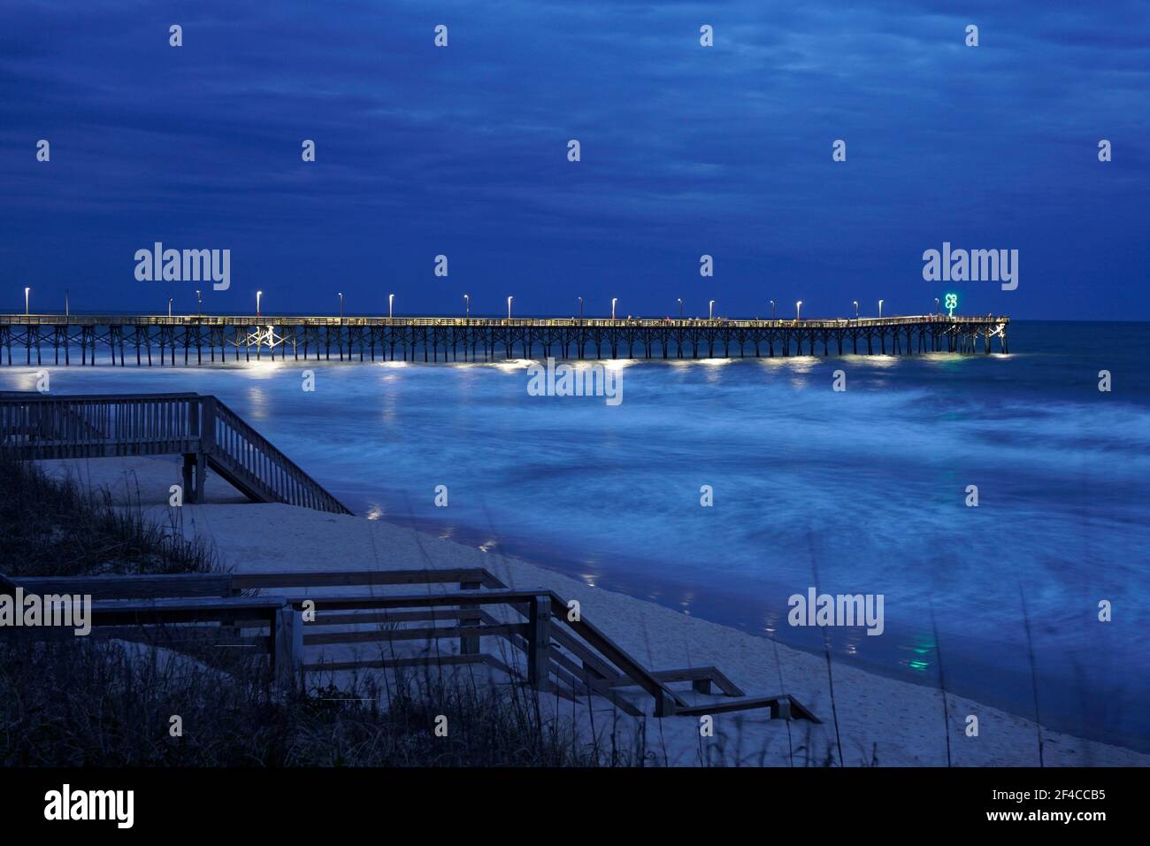 Die Wellen um den Surf City Pier in der Nacht verschwommen Stockfoto