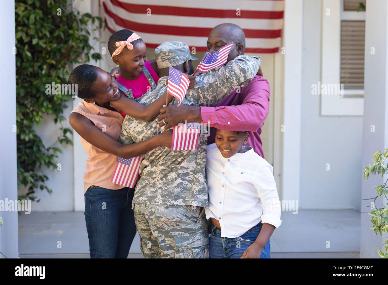 afroamerikanischer Soldat Vater umarmt Frau, Kinder und Vater vor dem Haus Stockfoto