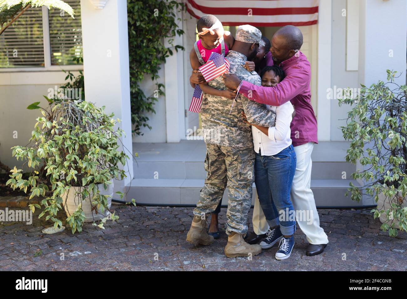 afroamerikanischer Soldat Vater umarmt Frau, Kinder und Vater vor ihrem Haus Stockfoto