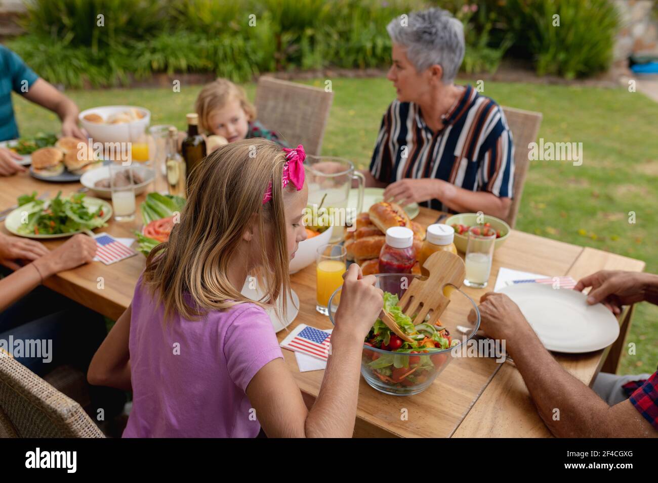 Kaukasische ältere Frau im Gespräch mit Familie Essen zusammen in Garten Stockfoto