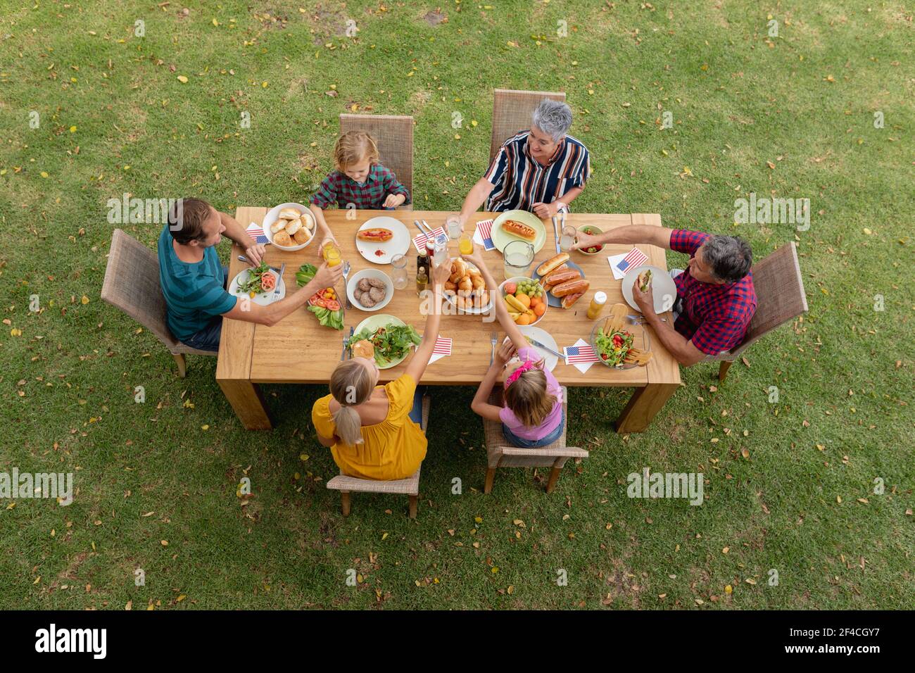 Blick von oben auf die kaukasische Familie mit drei Generationen beim Essen am Tisch Essen im Garten zum Toasten Stockfoto
