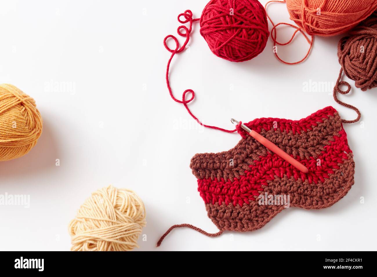 Buntes Häkelprojekt mit Haken und Garn, auf weißem Hintergrund. Stockfoto