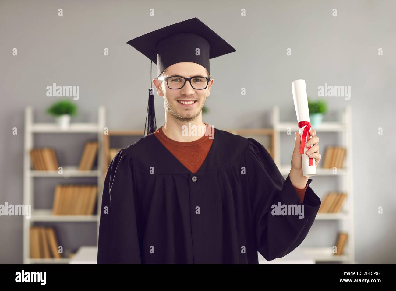 Portrait eines männlichen Studenten in Uniform mit Diplom in den Händen. Stockfoto