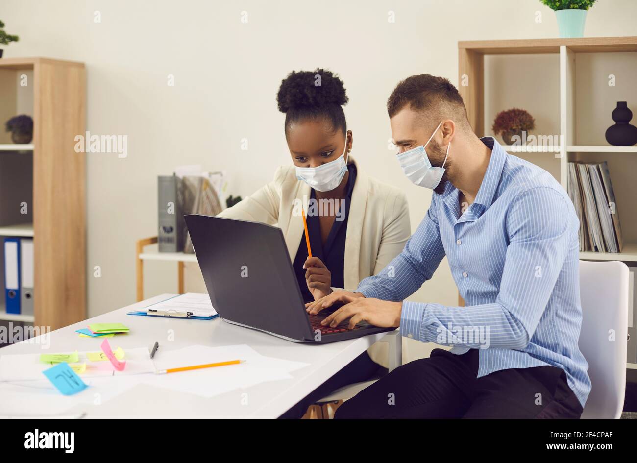 Interracial Business Worker Gesichtsmaske Kollegen arbeiten auf Laptop-Büro Hochformat Stockfoto