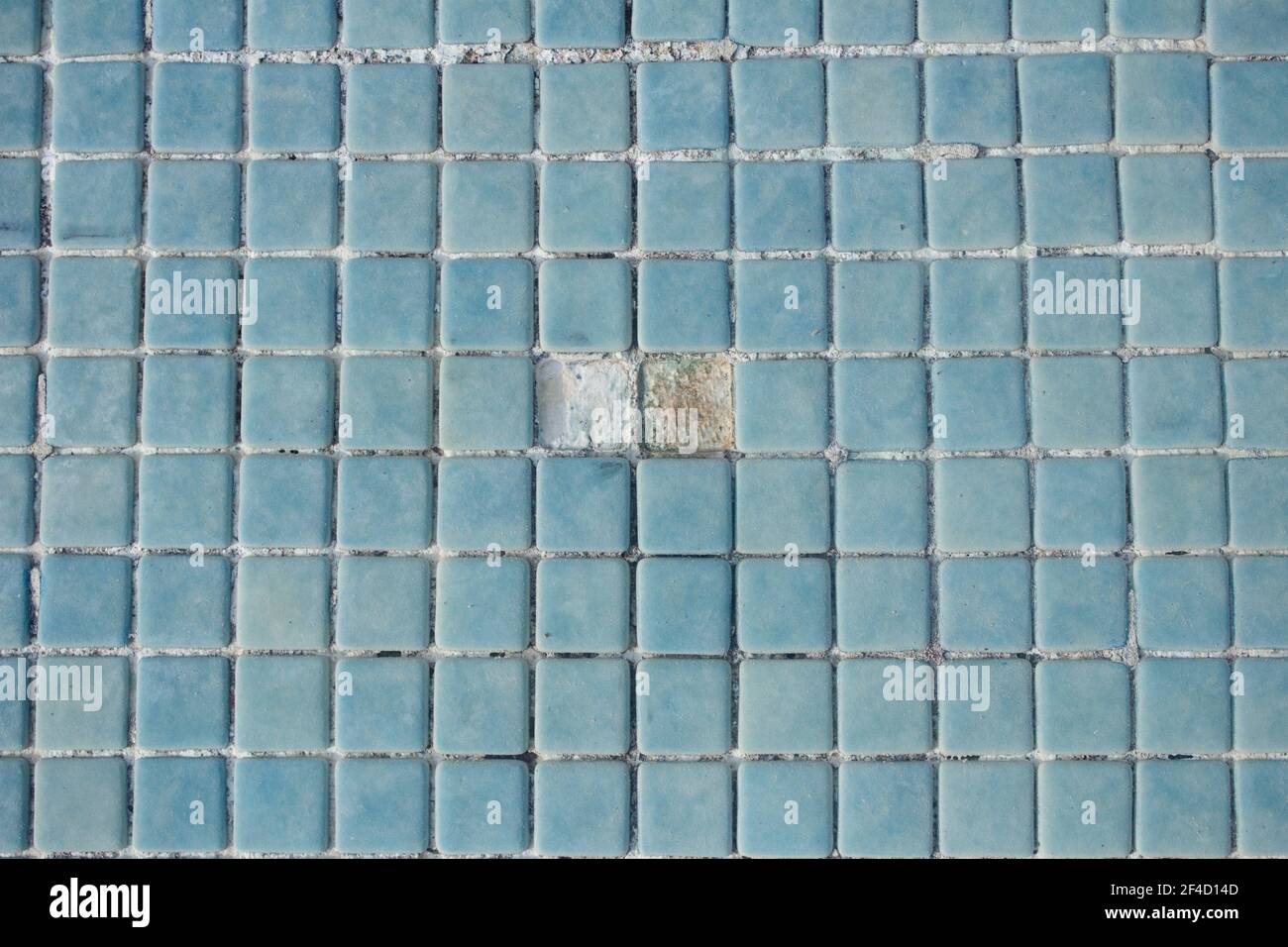 Zwei Löcher zusammen auf dem leeren Poolboden. Steinzeug Swimmingpool Boden, in dem zwei blaue Fliesen fehlen. Stockfoto