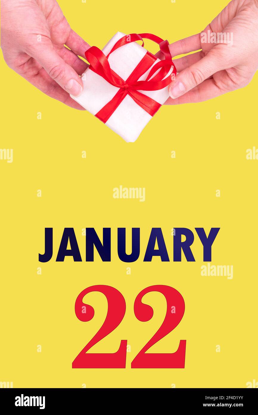 Januar 22nd. Festlicher Vertikaler Kalender Mit Händen Halten Weiße Geschenkschachtel Mit Rotem Band Und Kalender Datum 22 Januar Auf Illuminating Yellow Backgrou Stockfoto