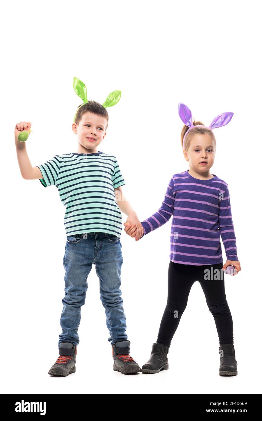 Junge Junge und Mädchen Freunde posieren mit Händen halten Ostereier und Hasen Ohren wegschauen. Ganzkörper isoliert auf weißem Hintergrund Stockfoto
