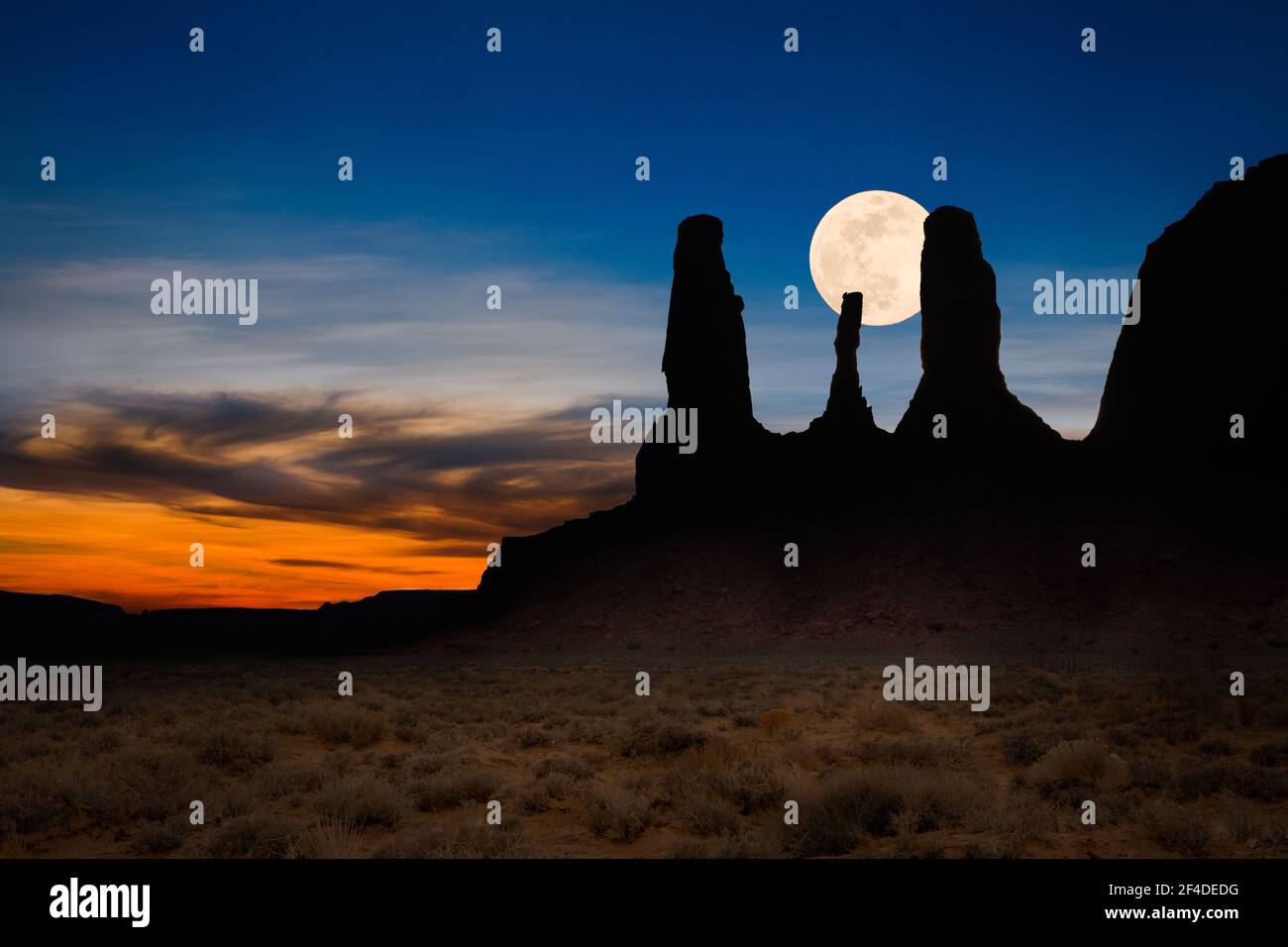 Mond steigt hinter einer Silhouette von Three Sisters, Monument Valley, Arizona, USA Stockfoto