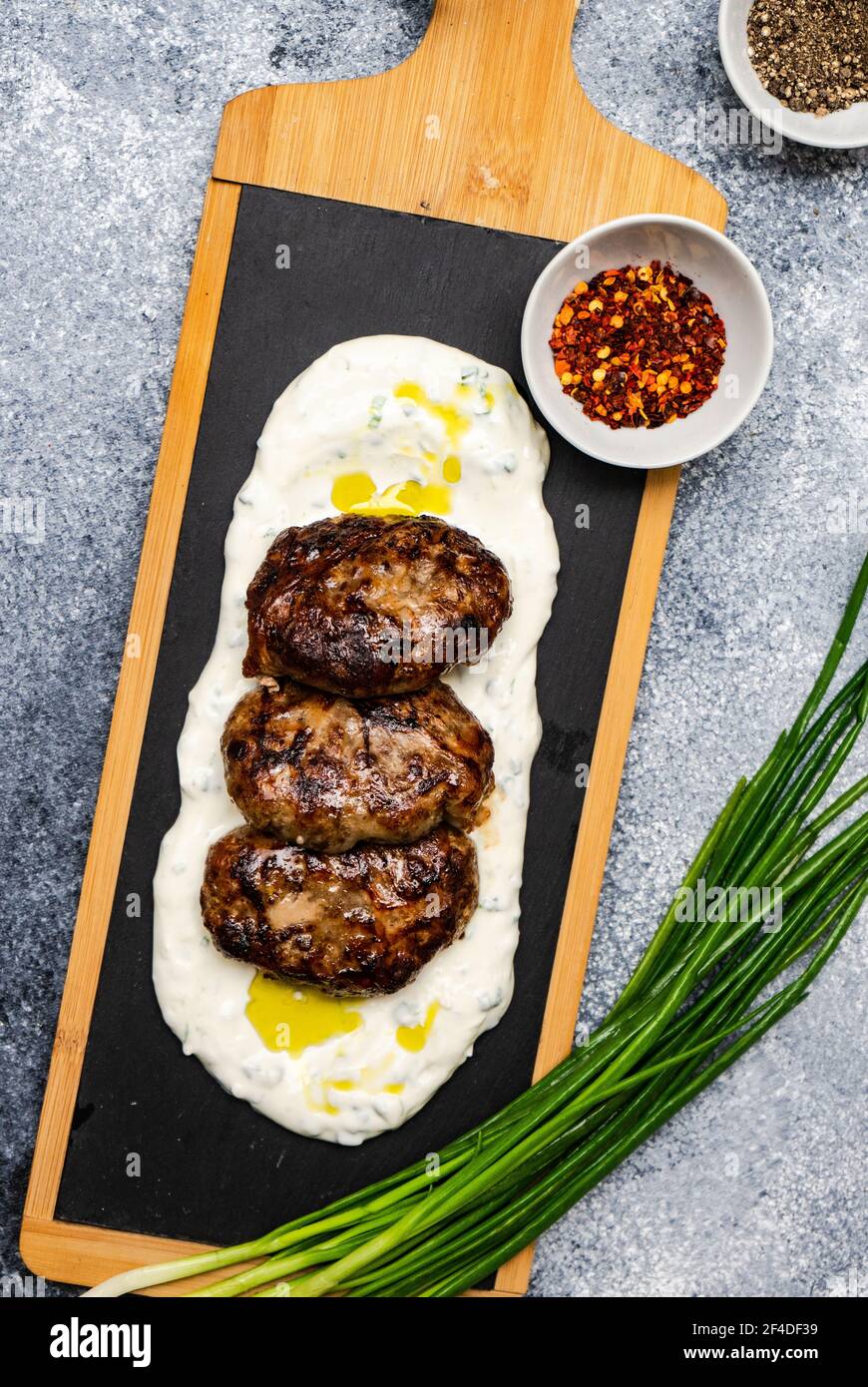 Overhead-Ansicht der georgischen Abchasura würzig gebratenen Fleischbällchen auf einem Bett aus saurer Sahne mit roten Chili-Flocken und schwarz Pfeffer Stockfoto