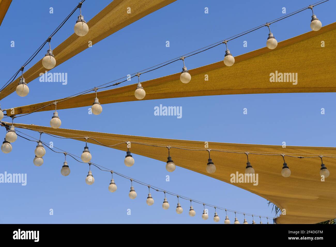 Dynamische Textur von Stoff Stretch-Dach aus Segeltuch mit Reihen von Lampen für Party-Nacht Beleuchtung auf blauen Himmel Hintergrund. Stockfoto