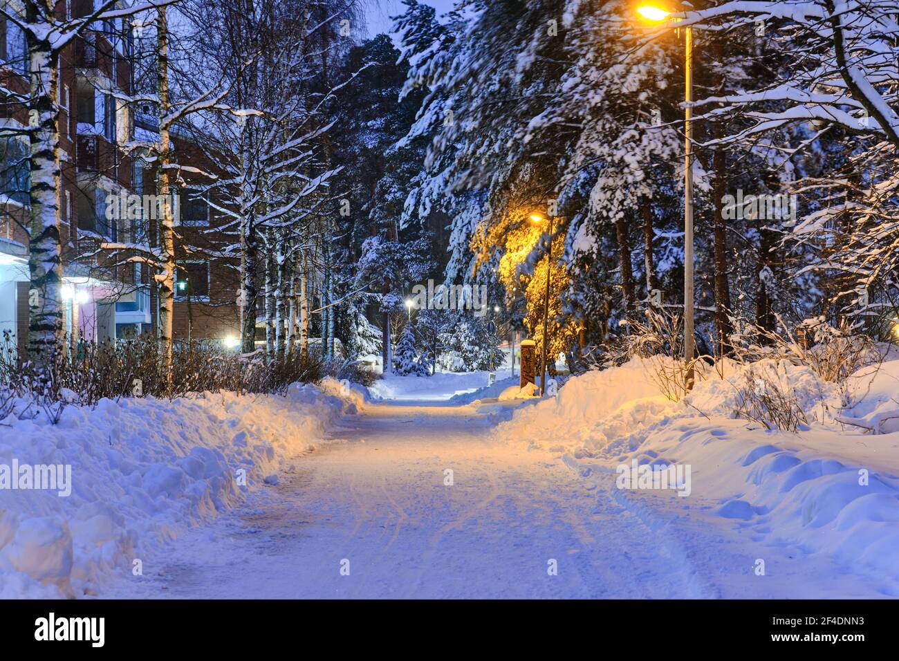 Schneebedeckte Fußgängerstraße im Wohnviertel nach einem Schneesturm am Morgen oder Abend in Finnland. Stockfoto