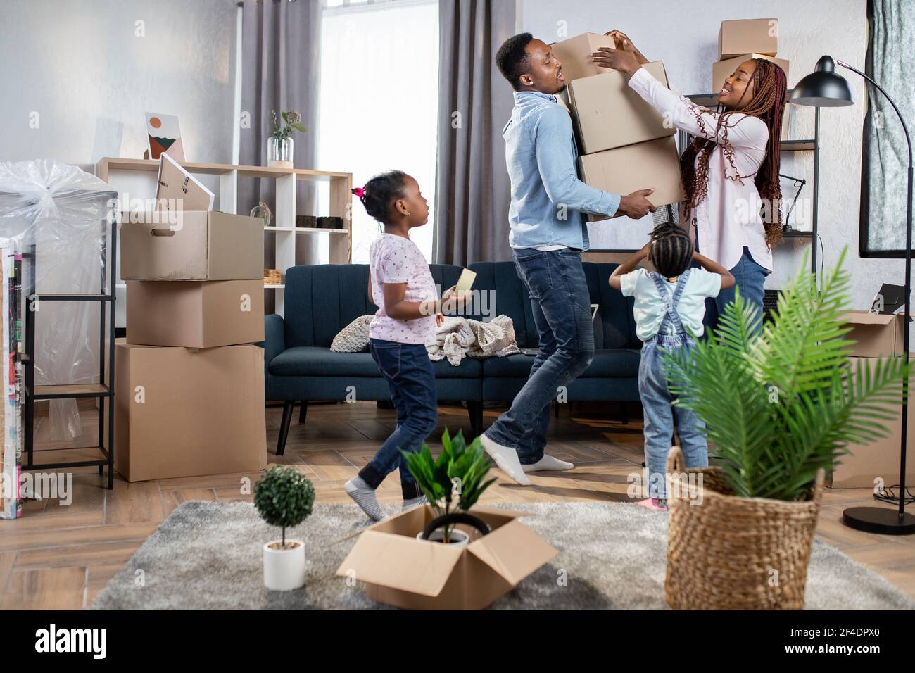 Afro-amerikanische Eltern und ihre beiden niedlichen Töchter Verpackung  Boxen. Junge Familie Glück beim Umzug in neue große Wohnung Stockfotografie  - Alamy