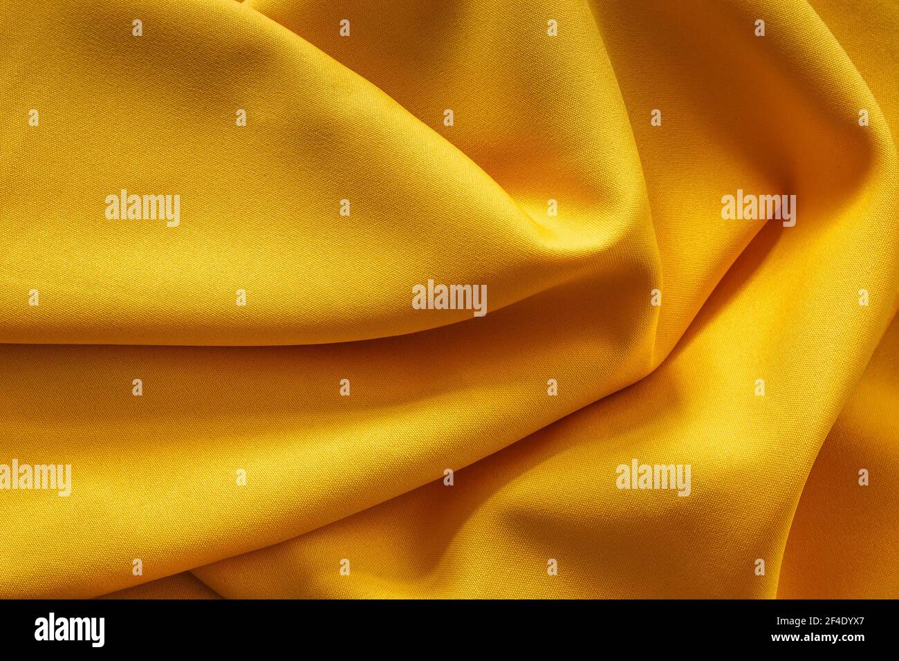 Gelbe Stoffstruktur.Frühlingsfarbe.Abstrakter gelber Hintergrund. Geschmeidiges, elegantes goldenes Textil. Trendfarbe des Jahres 2021. Farbe des Glücks, Herrlichkeit Stockfoto