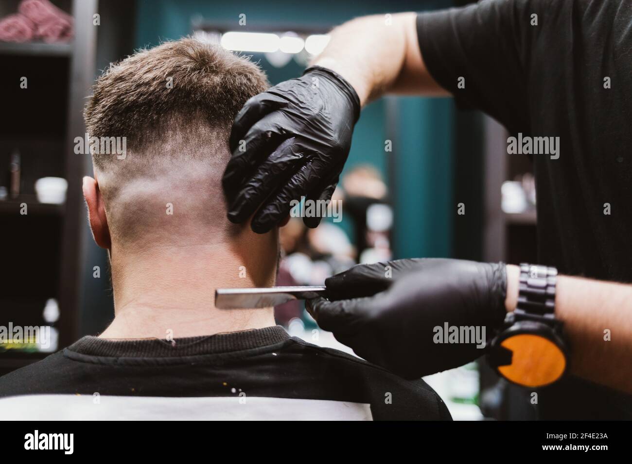 Männer Haarschnitt Prozess, Rückansicht des männlichen Kunden von Friseursalon sitzen im Stuhl, während professionelle Friseur rasiert seinen Hals und Rücken seines Kopfes wi Stockfoto