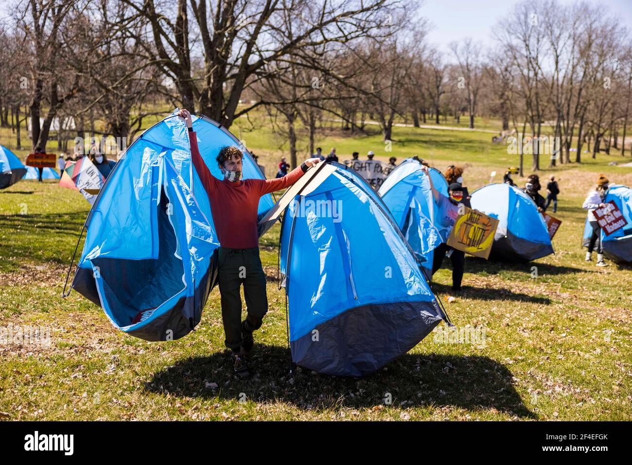 Patrick Saling trägt Zelte, die im Rahmen eines Protestes in den Reitfeldern nahe dem Memorial Stadium aufgestellt wurden. Eine Koalition von Mitgliedern der Bloomington-Gemeinschaft, Aktivisten, Und Indiana University Studenten marschieren von Dunn Meadow zu Simon Skjodt Assembly Hall während der "March to End the Madness", um gegen die City of Bloomington Behandlung von unbewohnten Bewohnern Pitching Zelte auf öffentlichem Eigentum und die 10 Millionen Dollar Abfindungszahlung Indiana University muss gefeuert zu zahlen Basketballtrainer Archie Miller für Herren. Mehrere Spiele für die NCAA Basketball-Turnier wurden innerhalb Assem gespielt Stockfoto