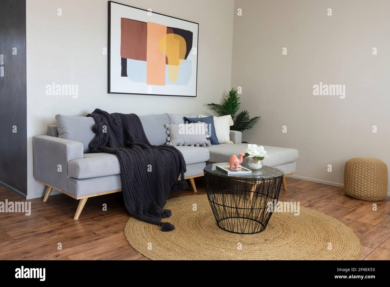 Stilvolles und komfortables, modernes Wohnzimmer mit einfachem Sofa und neutraler Einrichtung. Stockfoto