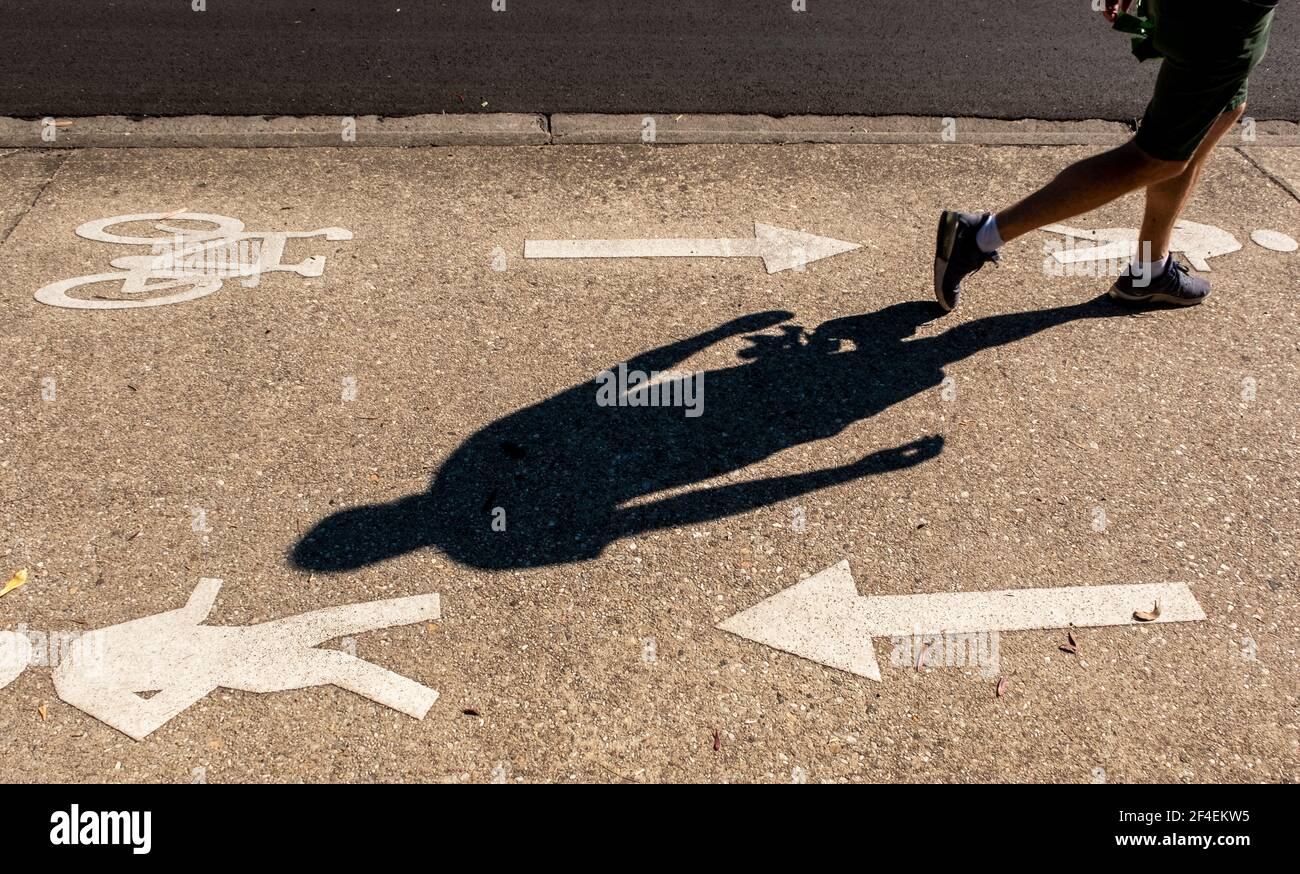 In Fairfield, Melbourne, Victoria, Australien, passiert ein Läufer Schilder und Symbole auf dem Fußweg für Fußgänger und Radfahrer Stockfoto
