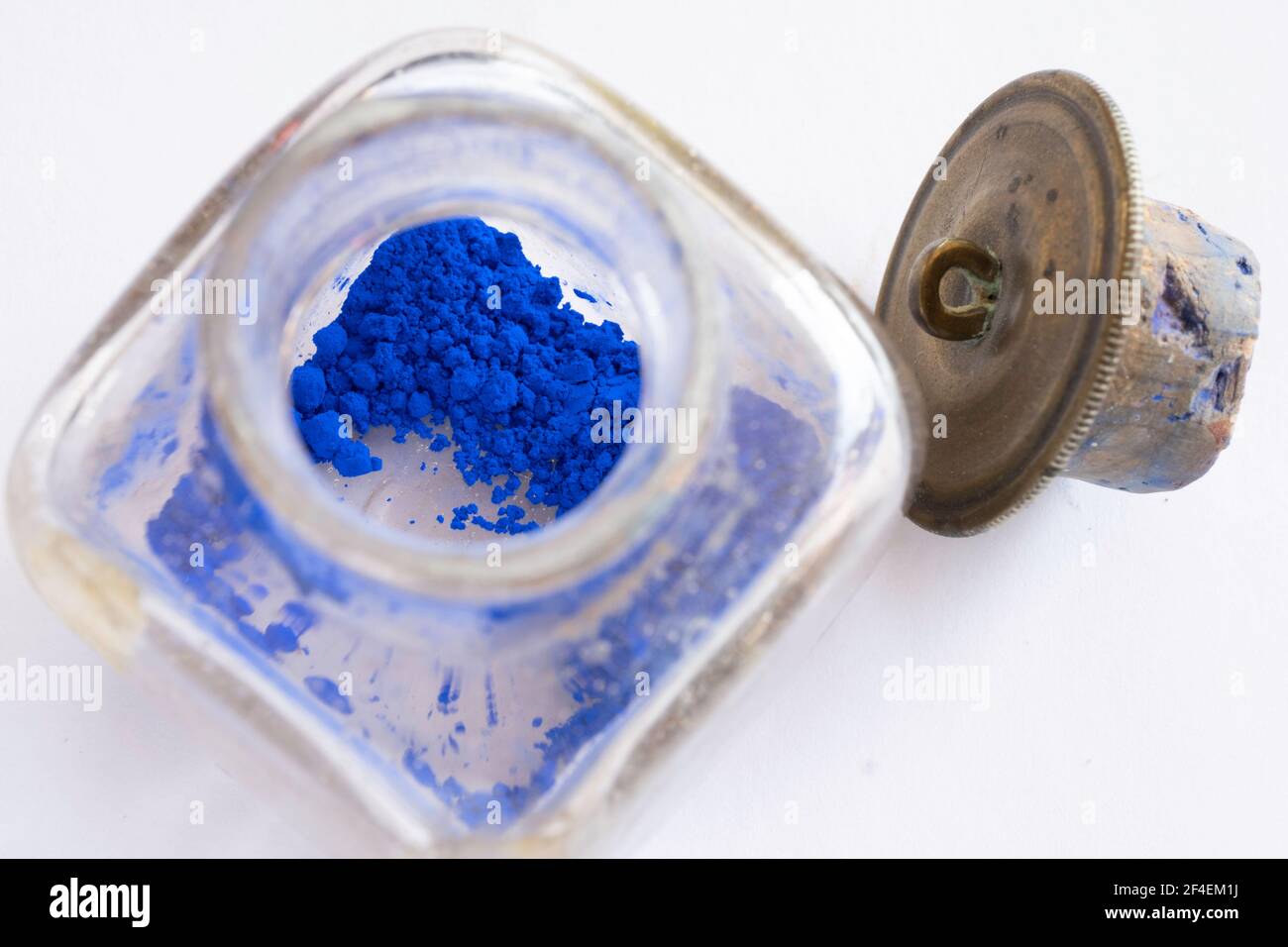 Altes Glas mit original kobaltblauen getrockneten Pigmentblöcken, um Ölfarbe für einen Maler zu machen. Daneben befindet sich der Kupferdeckel Stockfoto