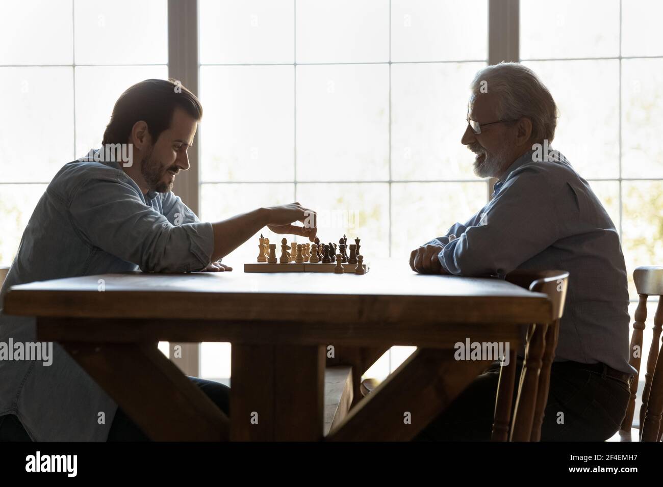 Glücklich reifen Vater spielen Schach mit erwachsenen Sohn Stockfoto
