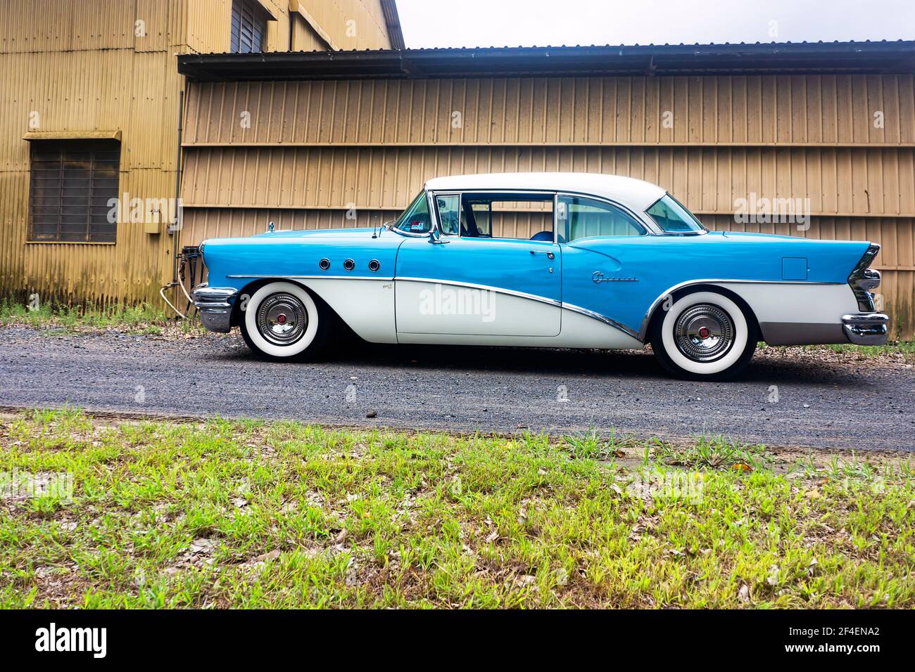 Seitenansicht einer restaurierten klassischen blauen 1955 Buick Limousine vor industriellem Hintergrund mit Kopierraum. Stockfoto