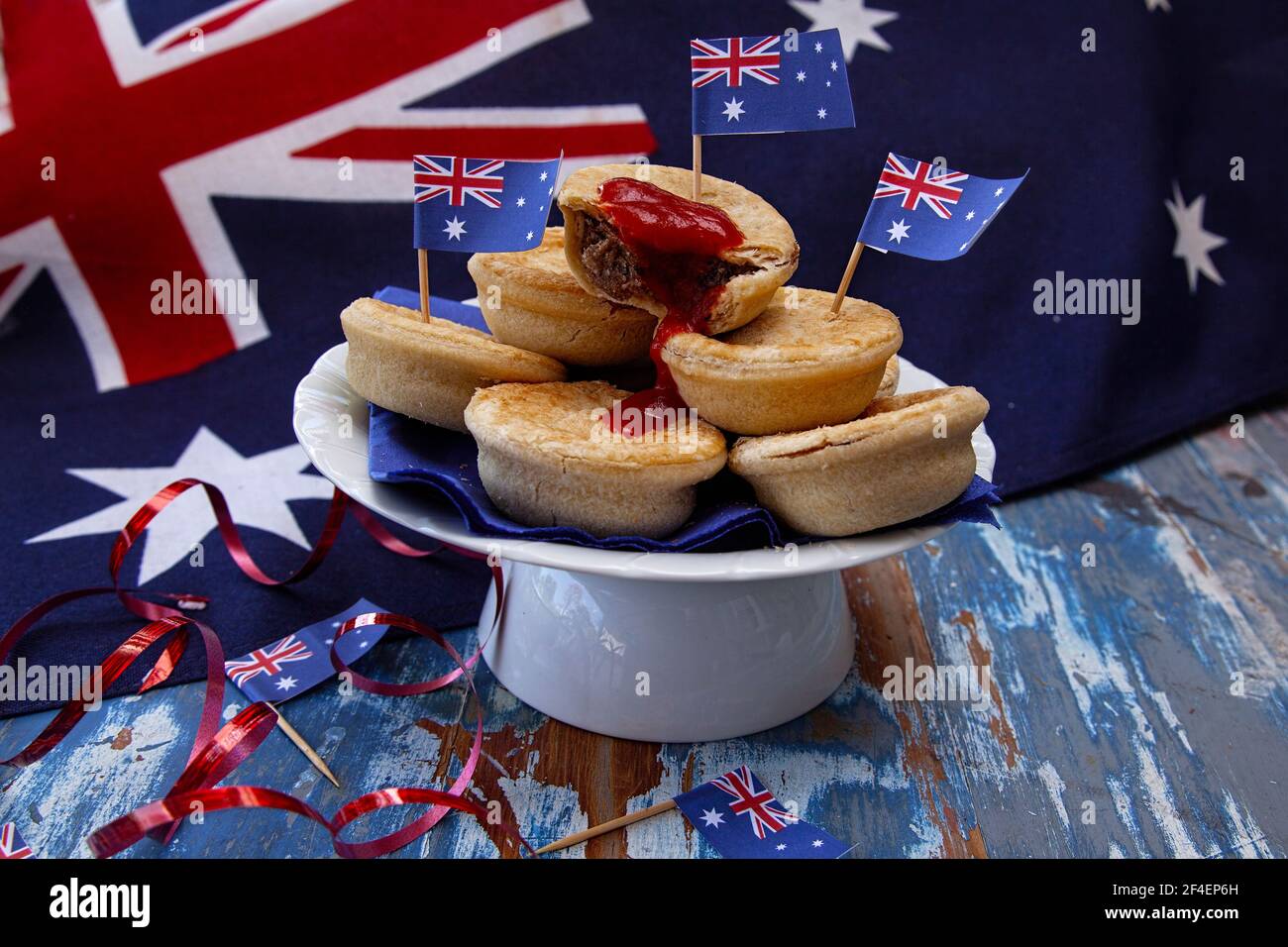 Ein Teller mit traditionellen Fleischpasteten mit Tomatensauce auf einer australischen Flagge für eine Australia Day Party oder einen Anzac Day. Stockfoto