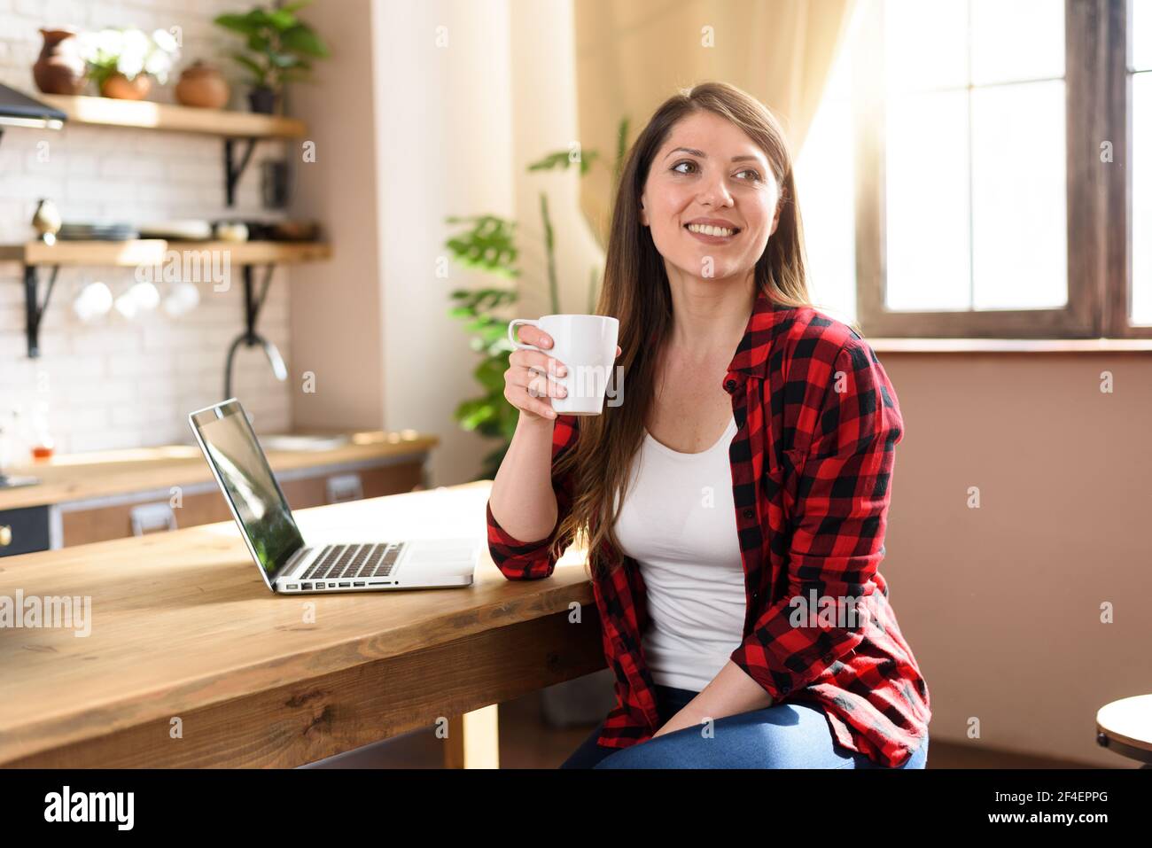 Frau surft im Internet mit ihrem Laptop mit einem weißen Bildschirm. Sie arbeitet zu Hause als Smart Working Stockfoto