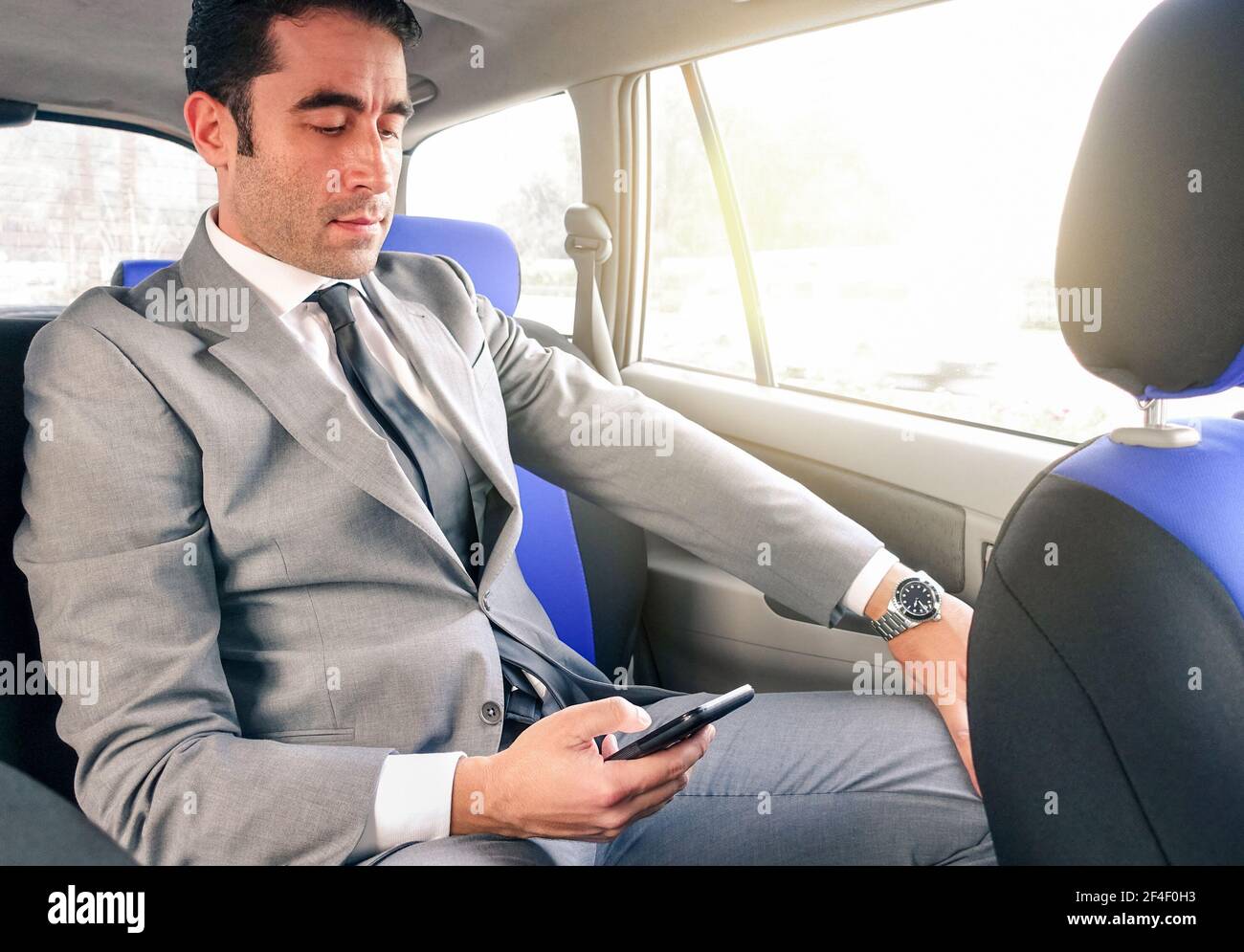 Junger, hübscher Geschäftsmann, der im Taxi sitzt und SMS schreibt Mit Smartphone - Business-Konzept mit modernem Mann mit smart Telefon Stockfoto