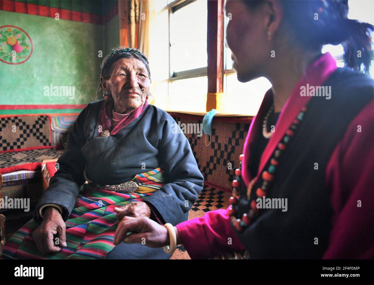 (210321) -- LHASA, 21. März 2021 (Xinhua) -- Basang (L) chattet mit ihrer Tochter in ihrem Haus im Ngamring Bezirk Xigaze, südwestlich von Chinas Autonomer Region Tibet, 27. Februar 2021. Basang, geboren 1936, pflegte Schafe für einen Leibeigenbesitzer zu weiden, um vor der demokratischen Reform 1959 um ein Leben zu betteln. Sie musste Wolle und Milch an den Leibeigenbesitzer als Steuer zahlen, und konnte nicht genug Nahrung und Kleidung haben. "Der Winter war die schwierigste Jahreszeit. Es waren acht Leute in meiner Familie, aber wir hatten kein Paar Schuhe." "Schafe weiden und barfuß auf der Farm arbeiten, ich beneide Tiere mit Hufen wirklich." Basa Stockfoto