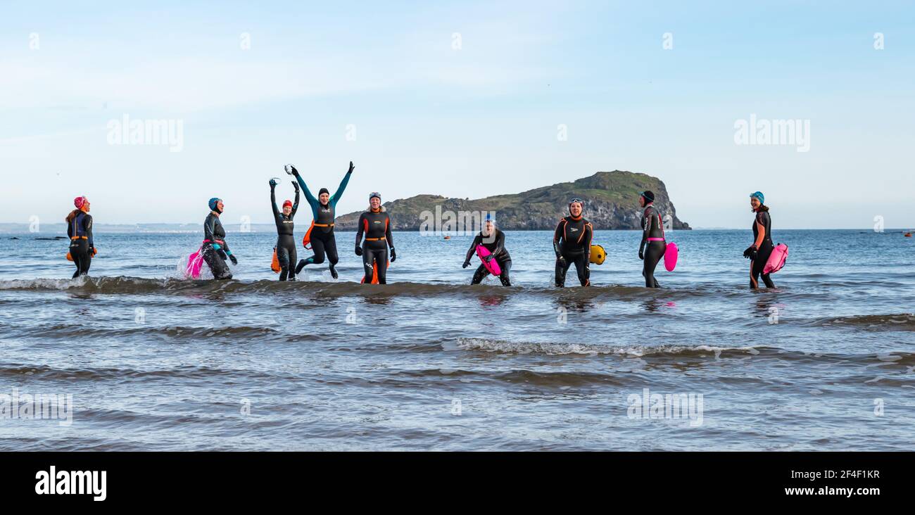 North Berwick, East Lothian, Schottland, Großbritannien, 21st. März 2021. UK Wetter: Wildschwimmer gehen im Firth of Forth im Freiwasser schwimmen. Wildbaden ist ein beliebter Sport für Einheimische in der Küstenstadt geworden. Diese Frauen tragen Neoprenanzüge und schwimmt gehen ins Wasser sind einige der Stammgäste, die in der Sport jede Woche während des ganzen Jahres in West Bay teilnehmen Stockfoto